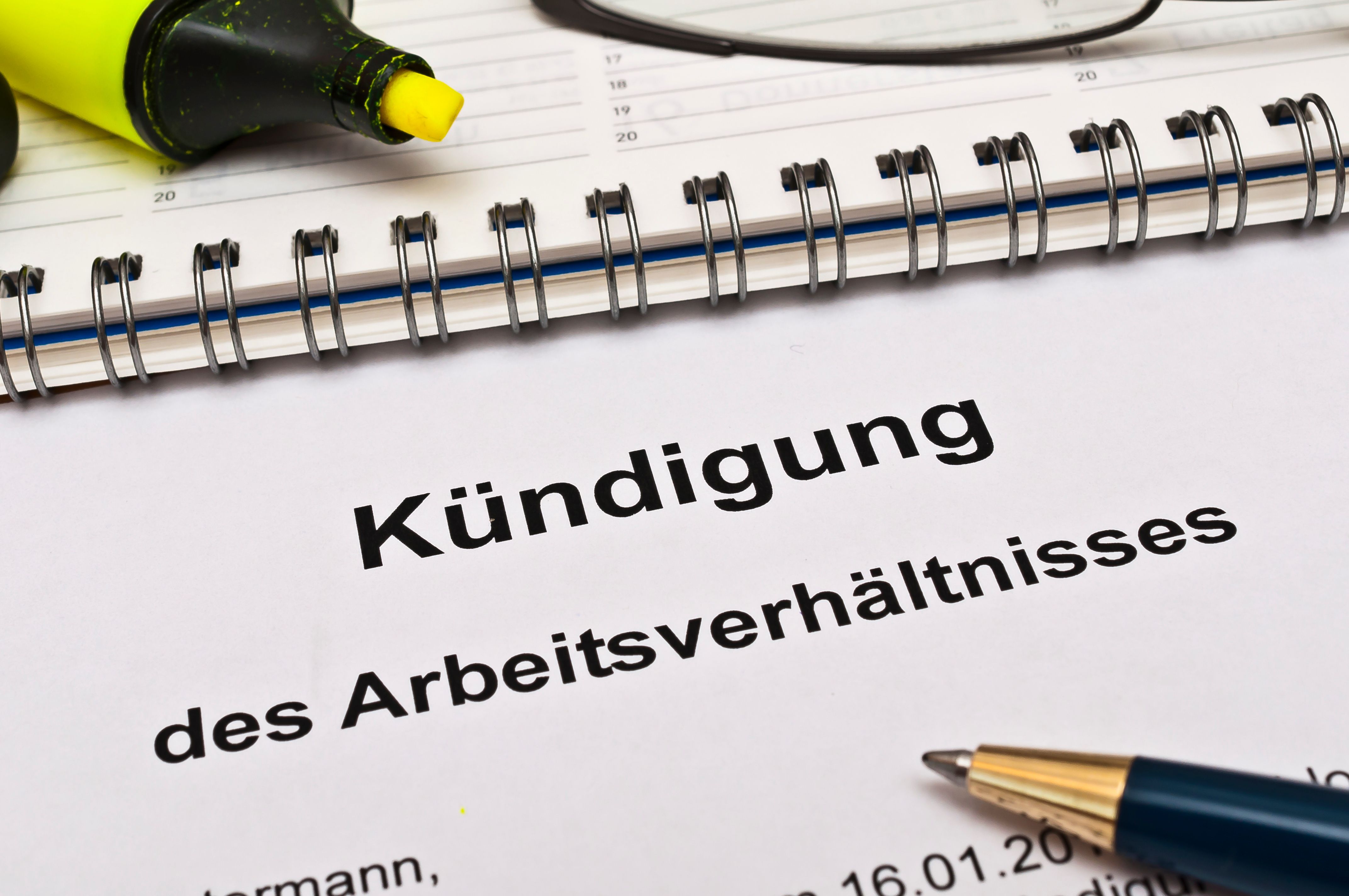 Dokument zur Kündigung eines Arbeitsverhältnisses mit Kalender, Stift und Textmarker als Symbol für Kündigungsfristen im Minijob.