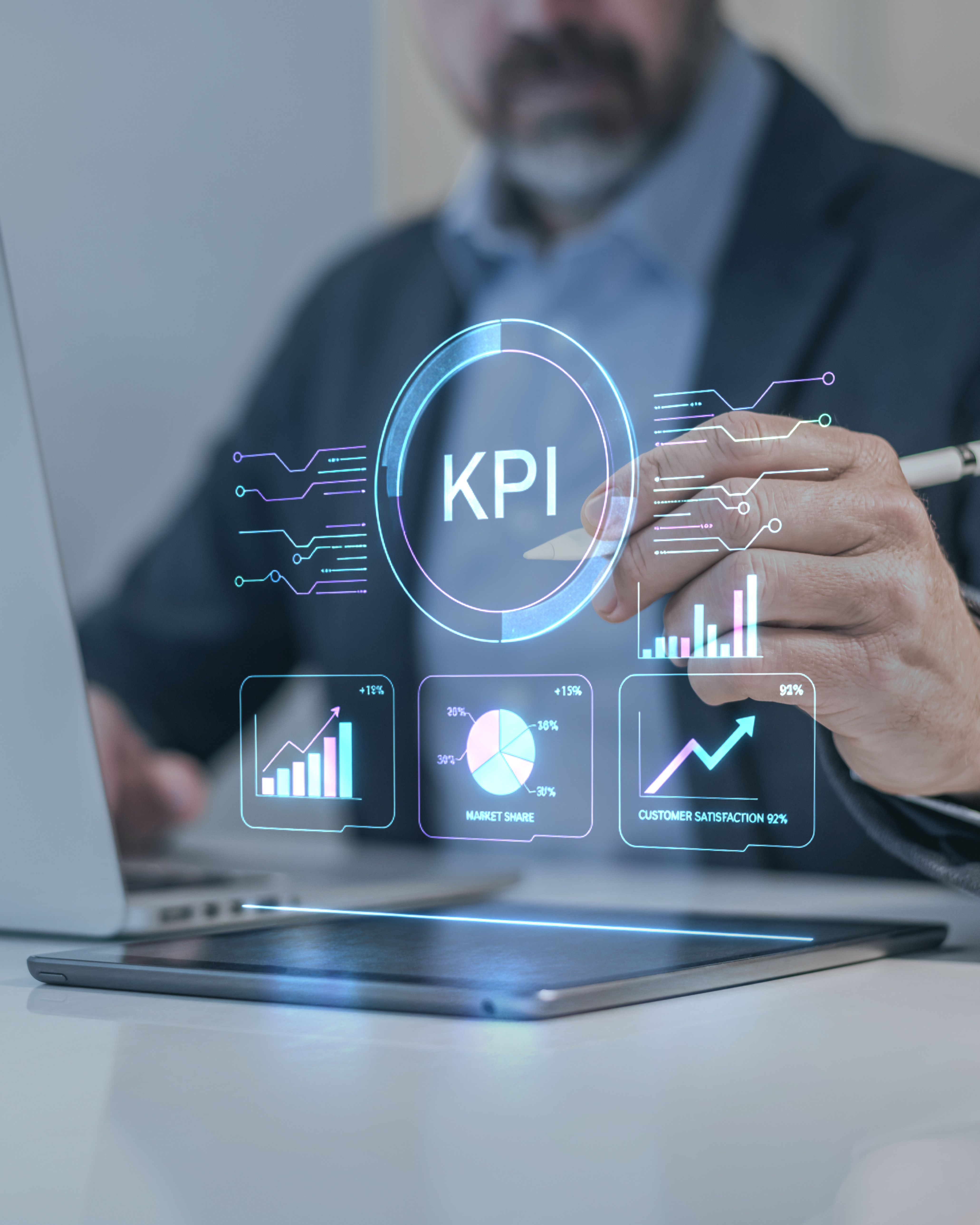 Person analysiert KPI-Dashboard mit Diagrammen auf Tablet und Laptop