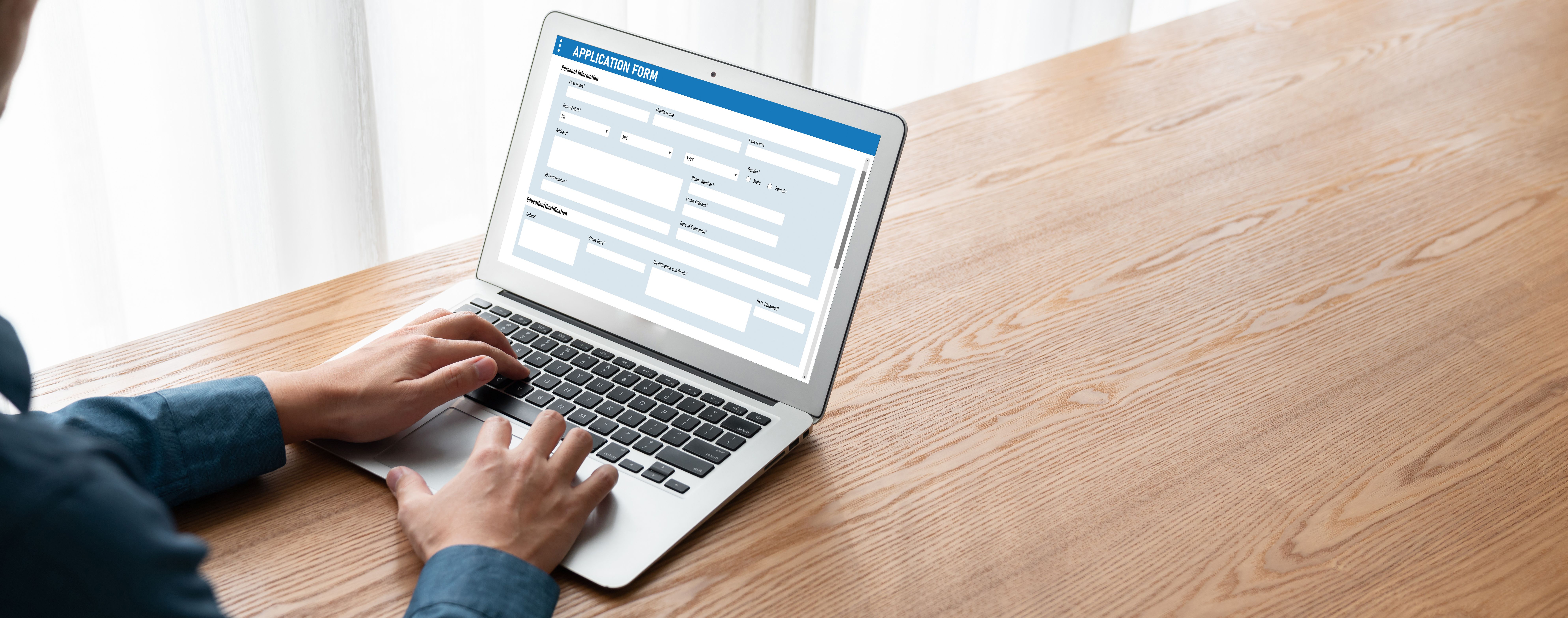 Person tippt auf Laptop und füllt ein Online-Bewerbungsformular aus