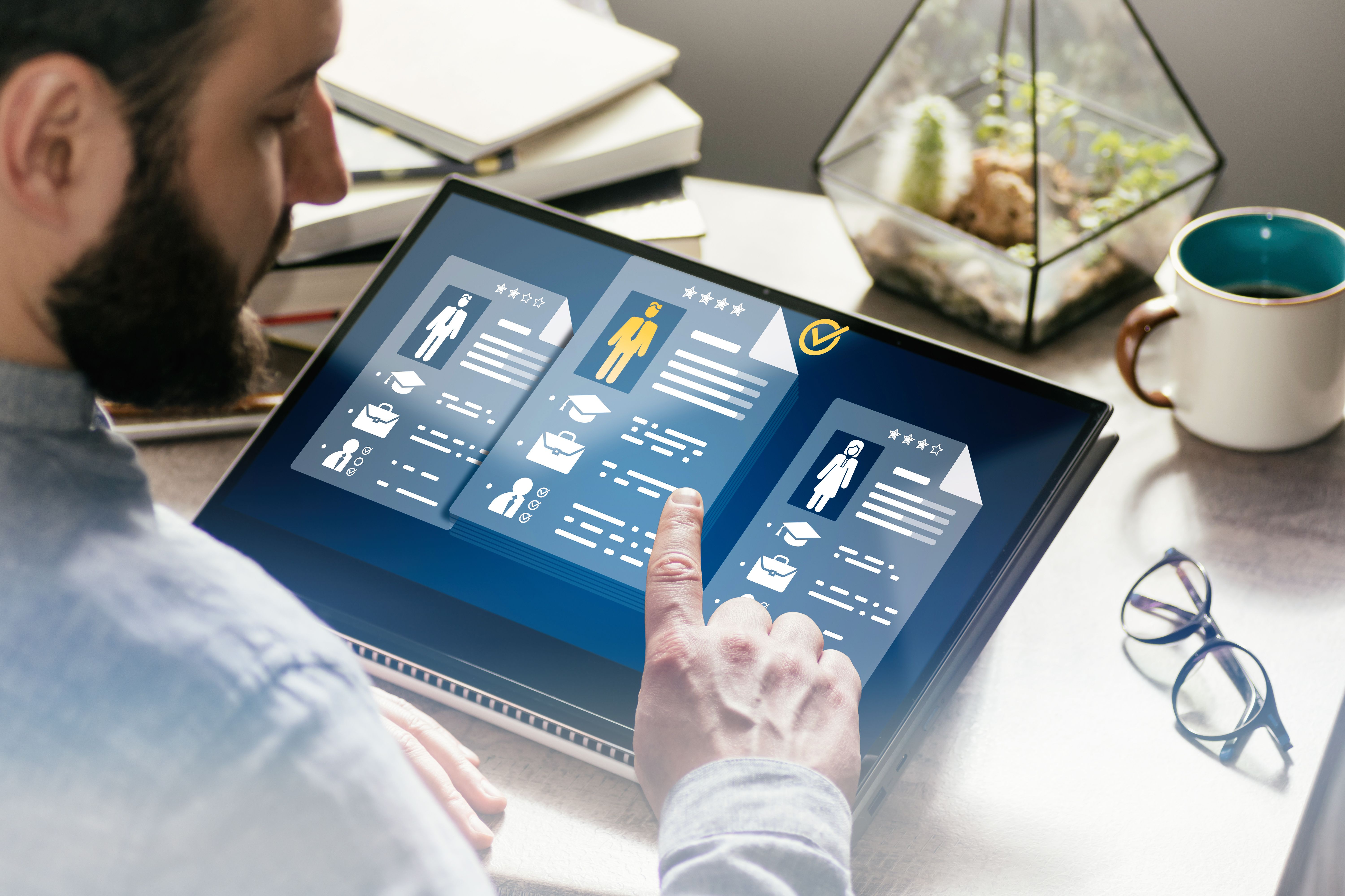 Person nutzt ein Tablet, um digitale Lebensläufe zu prüfen und Kandidaten auszuwählen – Darstellung von Online-Recruiting, HR-Screening und digitalem Bewerbungsprozess.