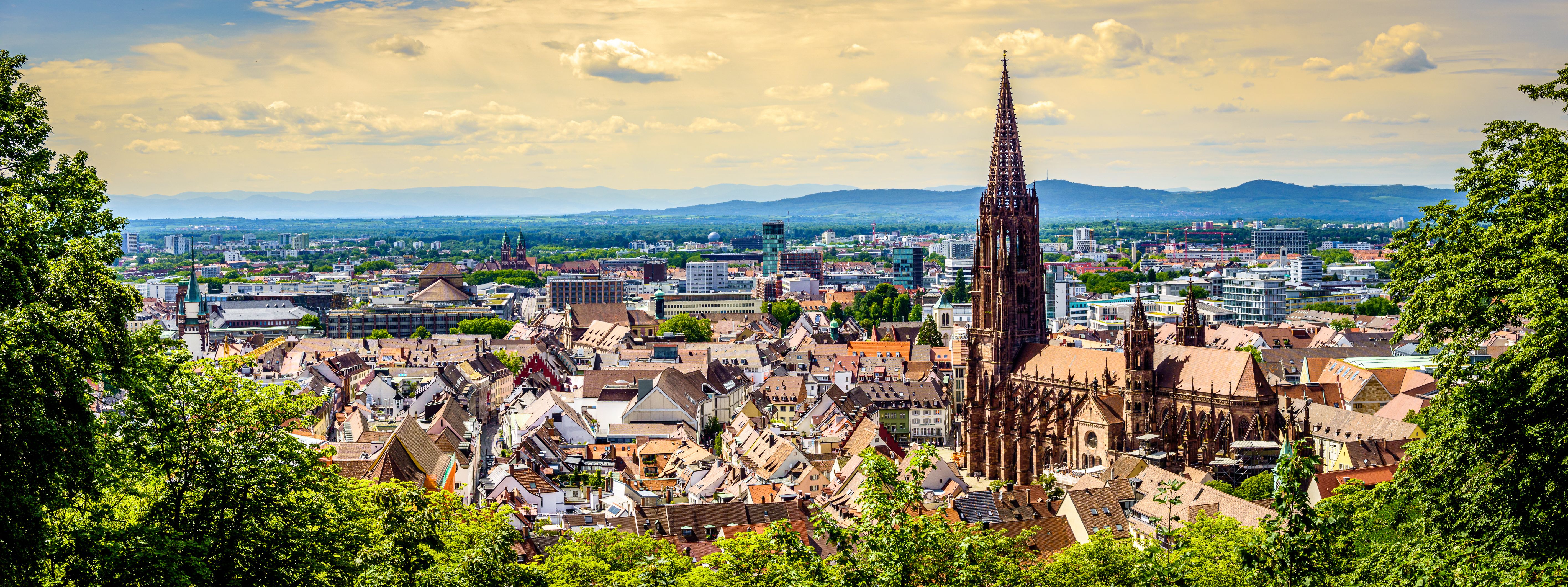 Panoramablick auf die Freiburger Altstadt mit dem Freiburger Münster und dem Schwarzwald im Hintergrund