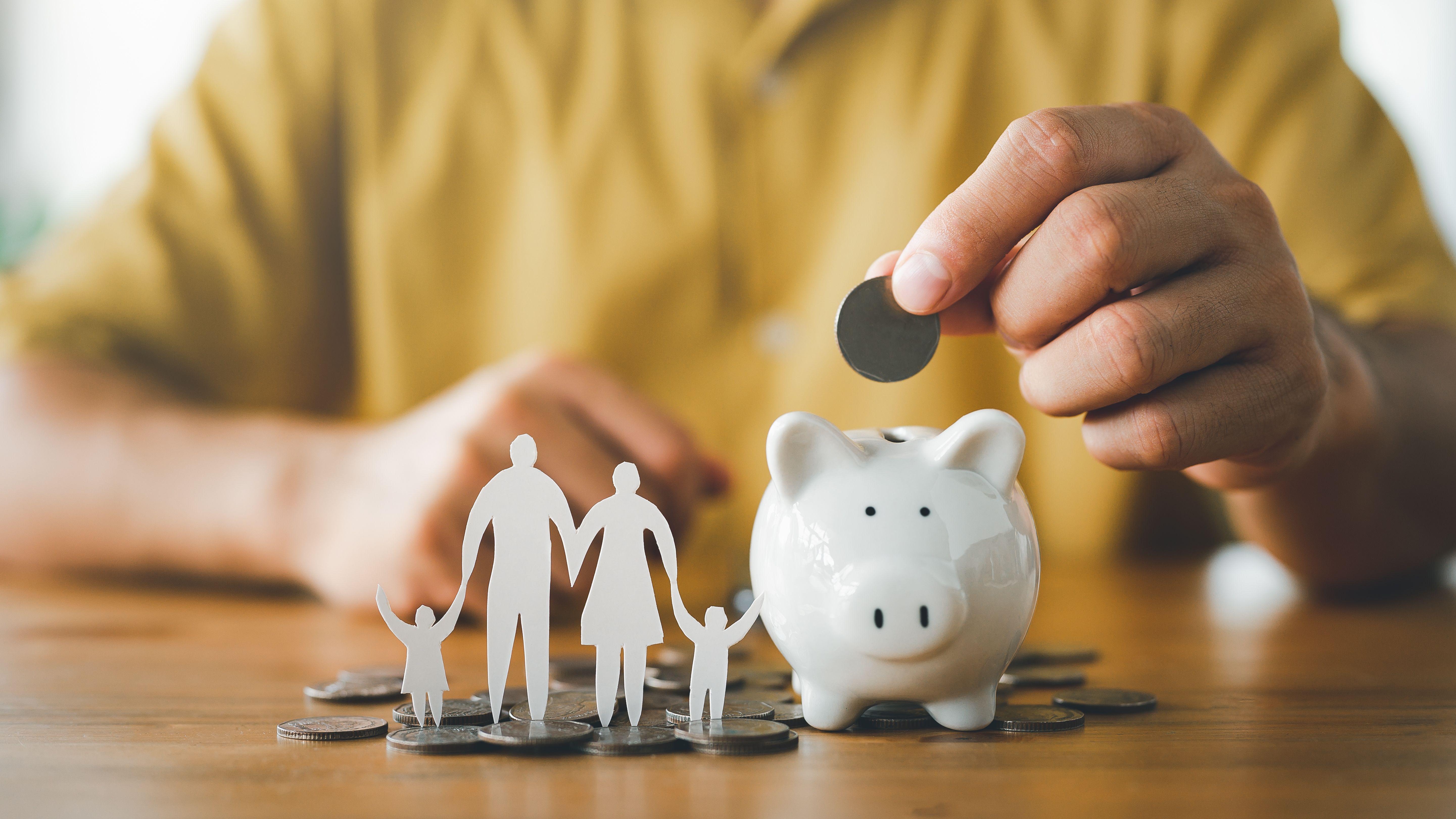 Sparschwein, Münzen und Familienfigur als Symbol für Elterngeld, finanzielle Absicherung und Elternzeit.