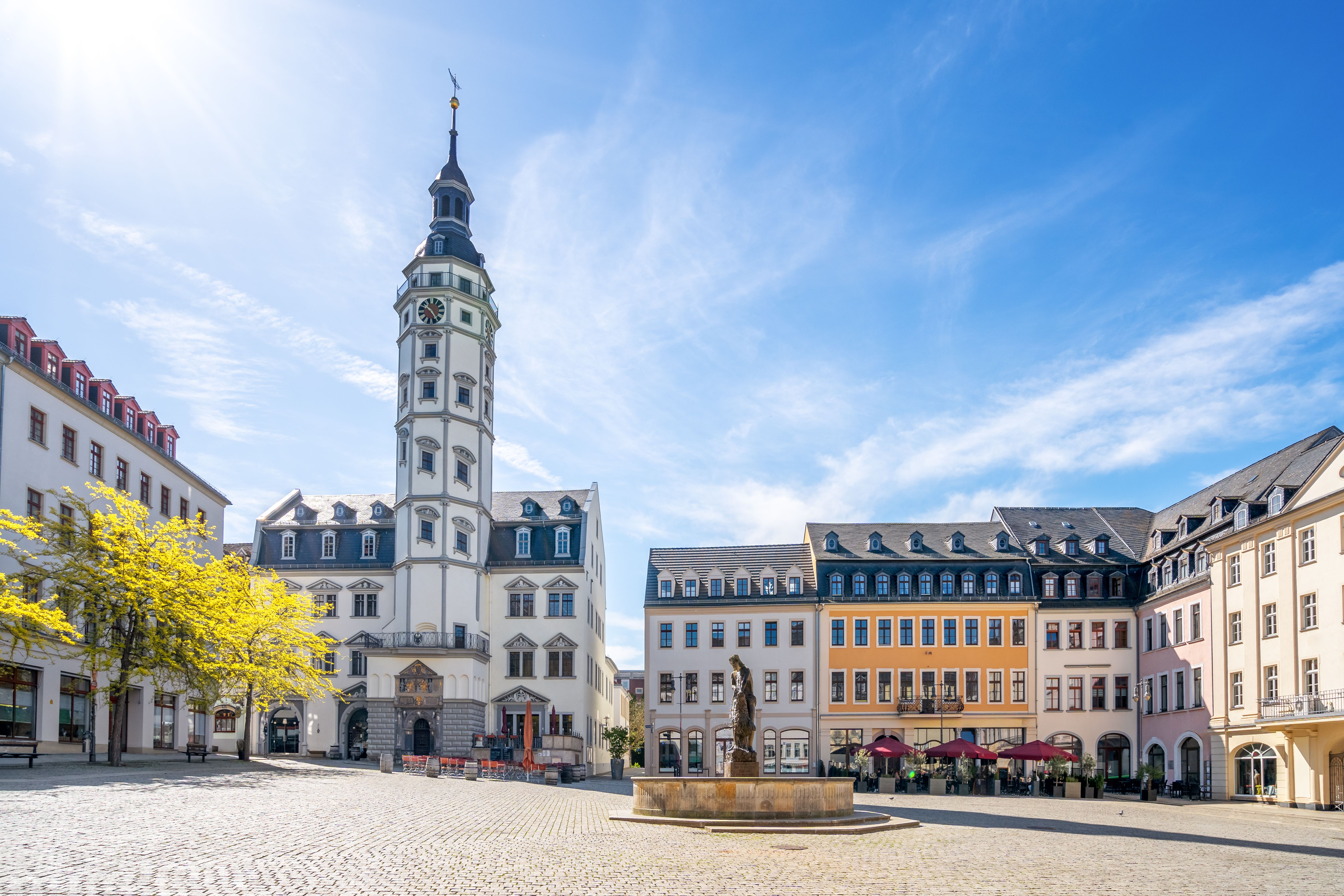 Historischer Marktplatz mit Rathaus und Brunnen im Zentrum von Gera in Ostthüringen unter blauem Himmel.