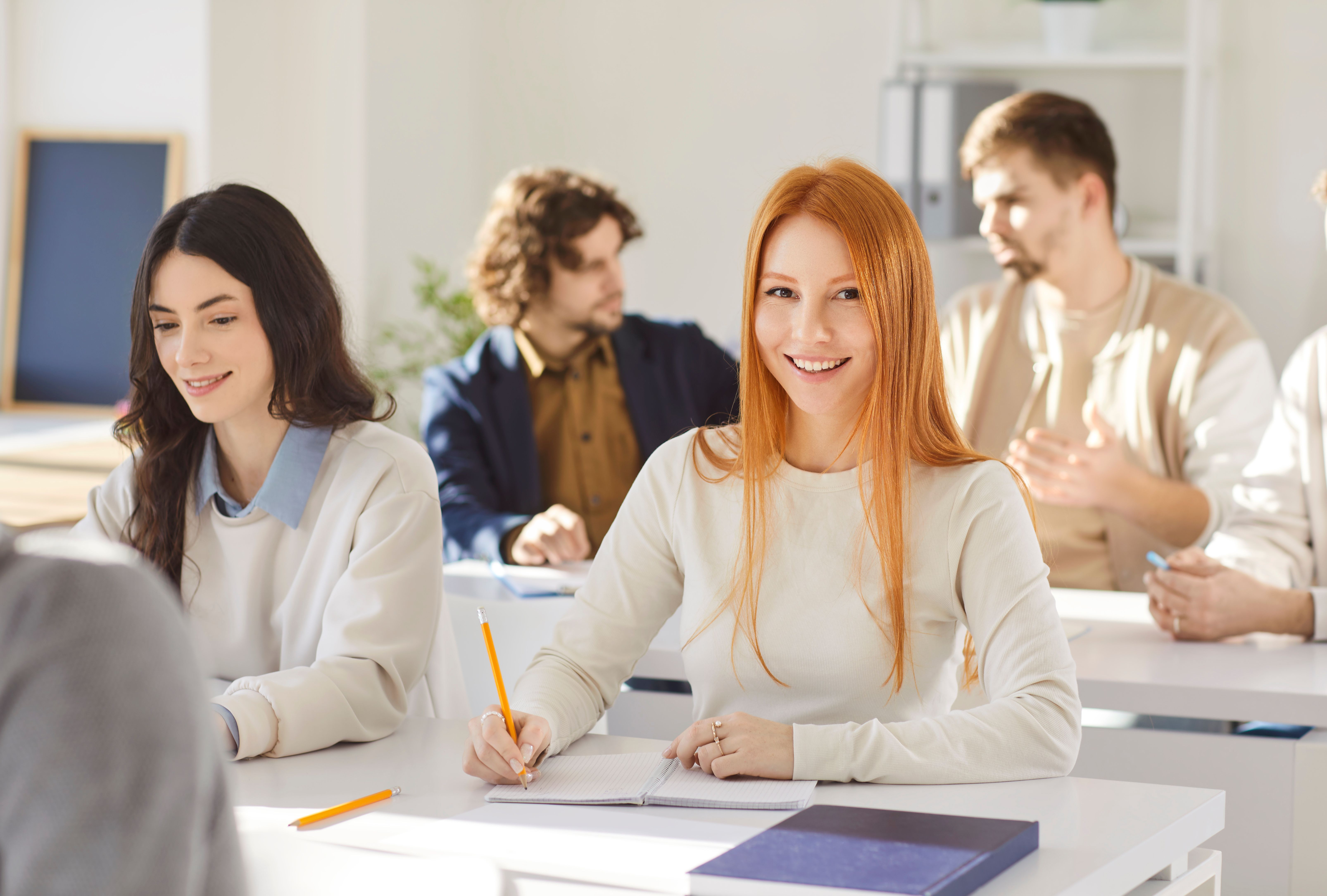Teilnehmende in einem Weiterbildungskurs im Seminarraum lernen gemeinsam und machen Notizen