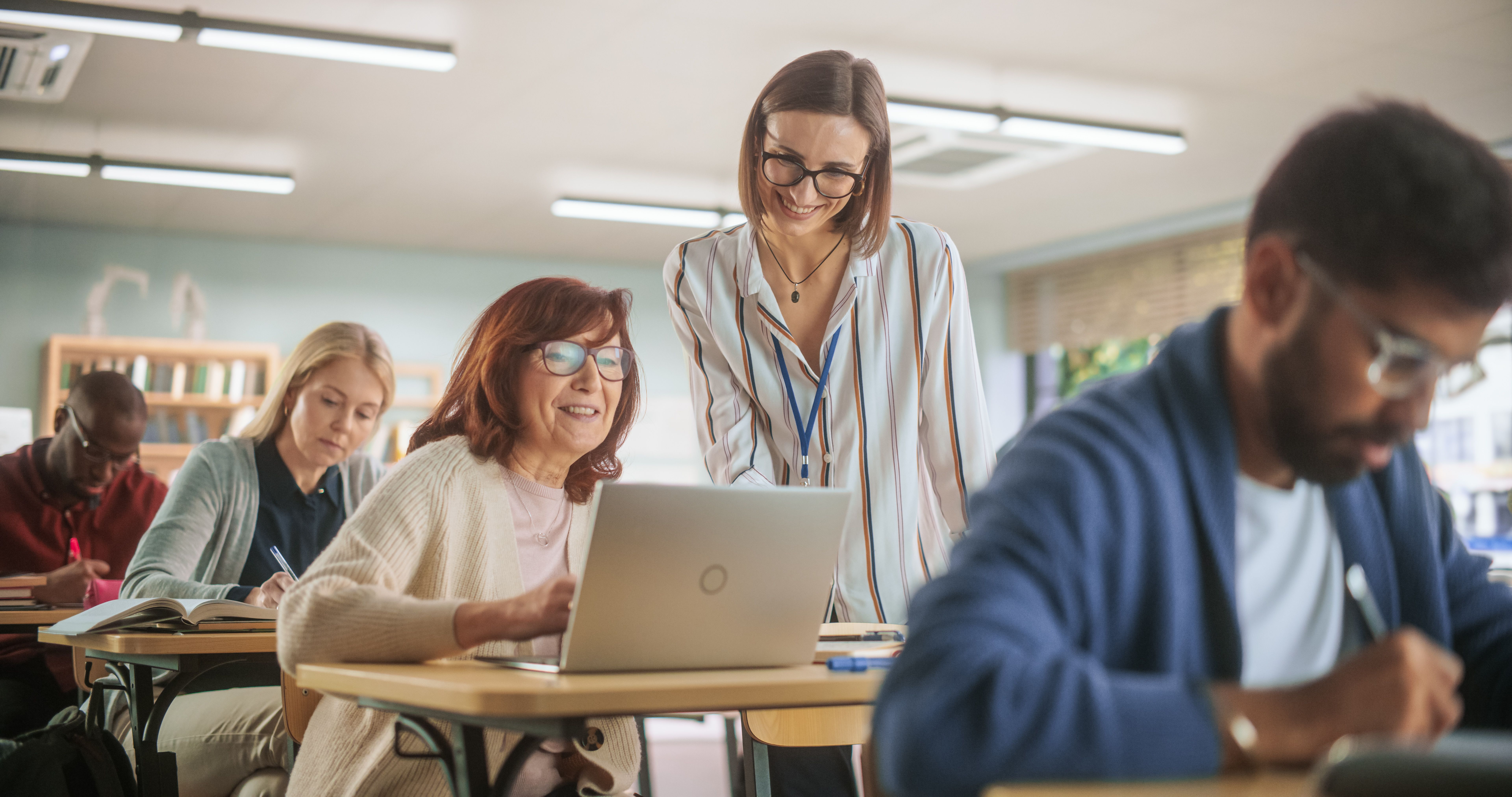 Teilnehmer in Weiterbildungskurs arbeiten gemeinsam im Seminarraum.