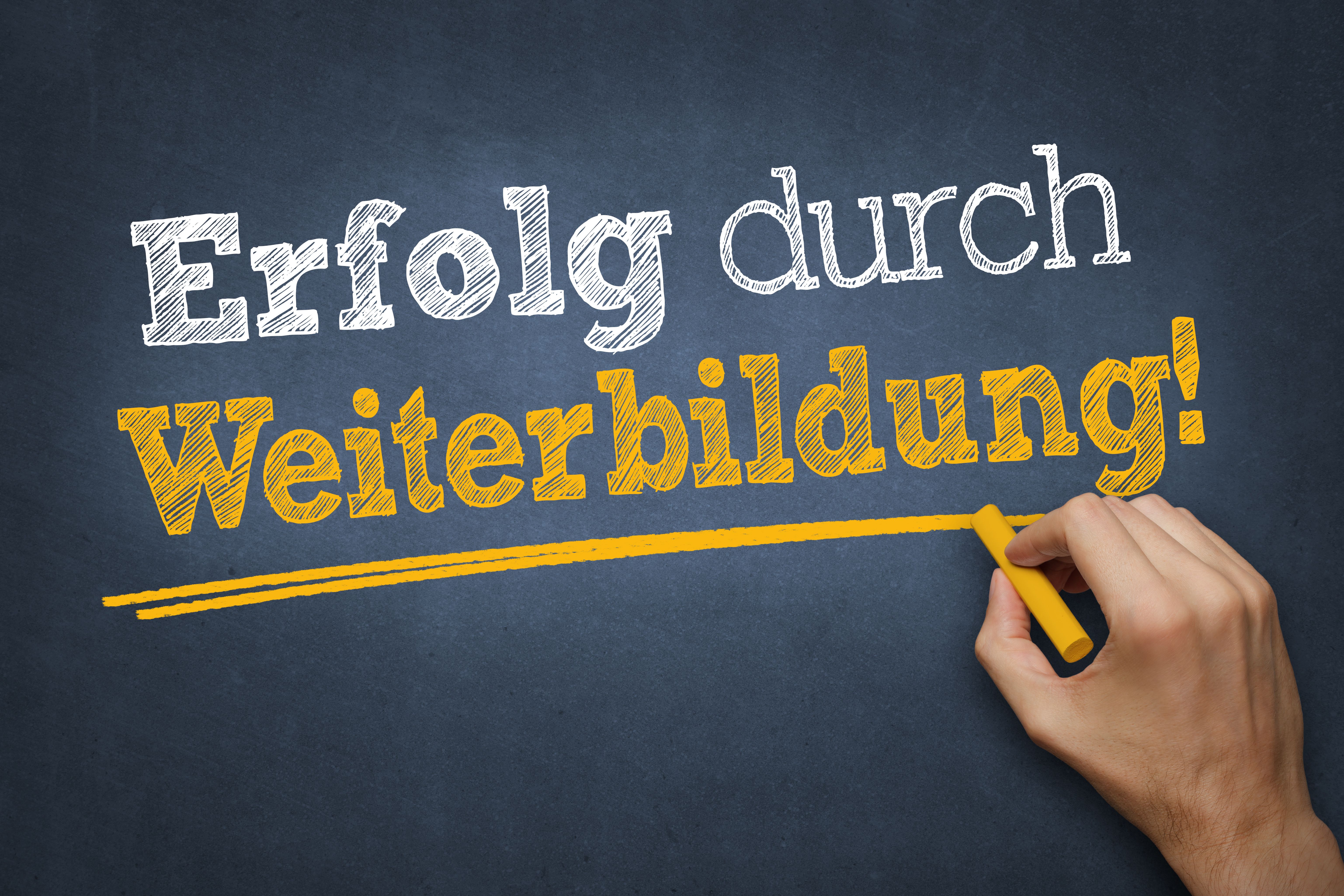 Tafel mit Schriftzug „Erfolg durch Weiterbildung“.